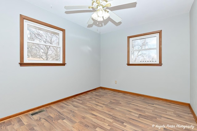 empty room featuring ceiling fan, light wood finished floors, visible vents, and baseboards