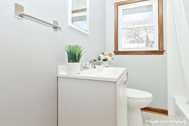 bathroom with toilet, a tub, and vanity