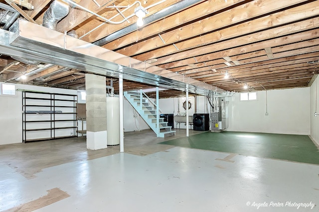 basement featuring gas water heater, heating unit, and stairs