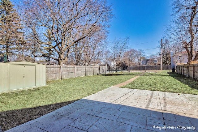 view of yard with a storage shed, a patio, a fenced backyard, a trampoline, and an outdoor structure