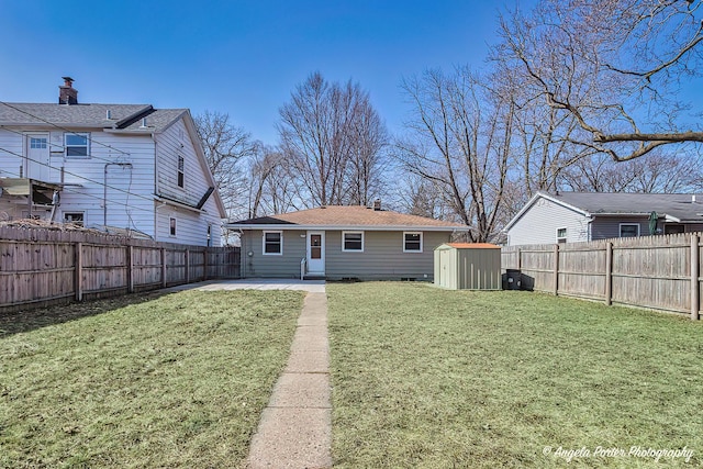 back of house featuring a yard, a patio, a shed, a fenced backyard, and an outdoor structure