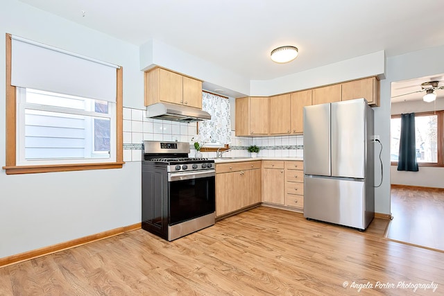 kitchen with appliances with stainless steel finishes, light countertops, light brown cabinets, and under cabinet range hood