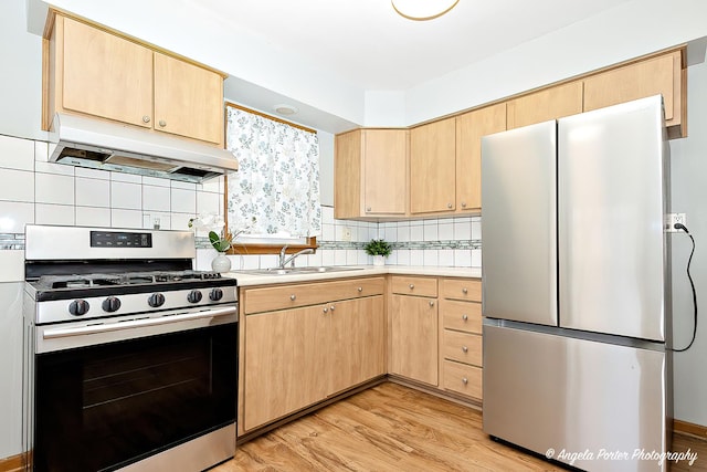 kitchen featuring under cabinet range hood, light brown cabinets, and stainless steel appliances