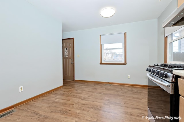 kitchen featuring stainless steel gas range oven, light wood-style flooring, exhaust hood, visible vents, and baseboards