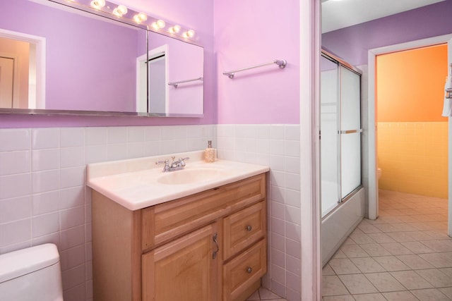 full bathroom featuring vanity, toilet, and tile walls