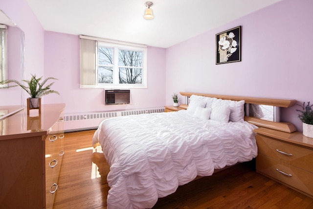 bedroom with a wall mounted AC, radiator heating unit, and wood finished floors