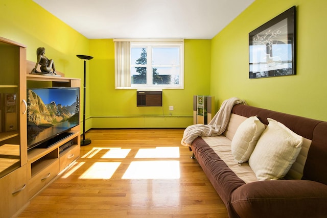 living area featuring an AC wall unit, wood finished floors, and baseboard heating