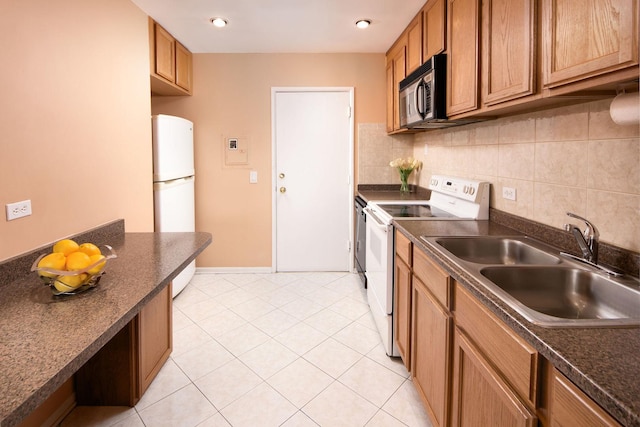 kitchen with a sink, white appliances, dark countertops, and tasteful backsplash