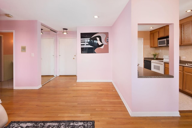 corridor with recessed lighting, light wood-type flooring, and baseboards