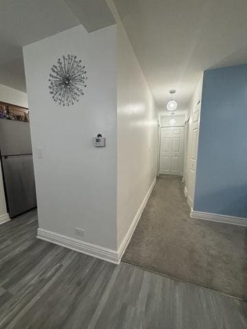 corridor featuring dark wood finished floors and baseboards