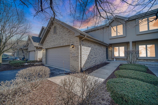 view of front of house featuring driveway, brick siding, and an attached garage