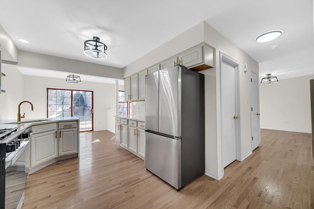 kitchen with appliances with stainless steel finishes, light countertops, light wood-style floors, and a sink