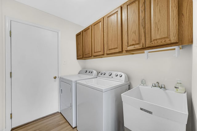 laundry area with cabinet space, light wood-style floors, a sink, and independent washer and dryer