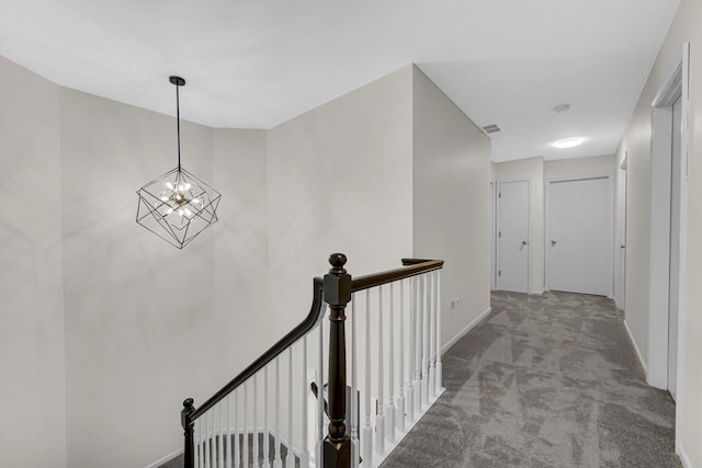 corridor featuring carpet, visible vents, an upstairs landing, a chandelier, and baseboards