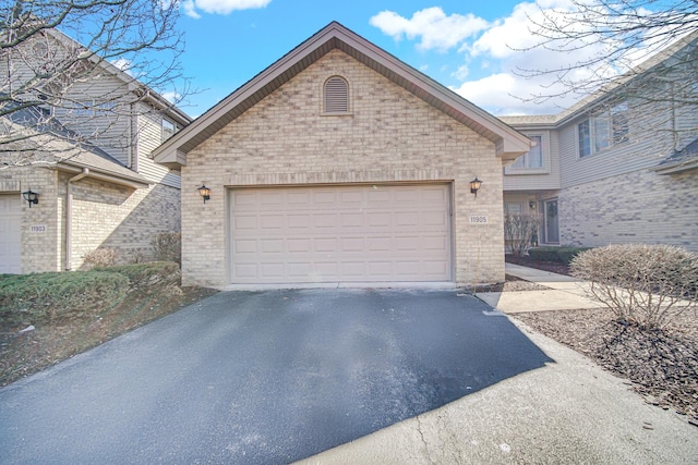 view of front of property featuring an attached garage, aphalt driveway, and brick siding