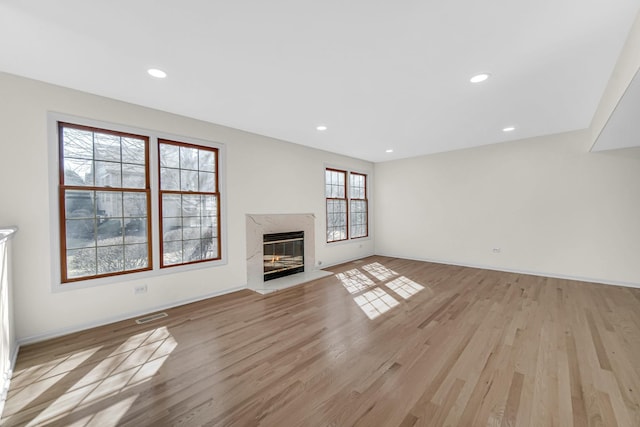 unfurnished living room with a high end fireplace, light wood finished floors, and recessed lighting