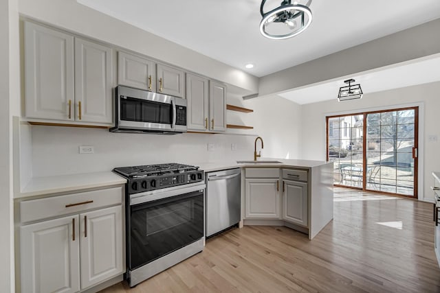 kitchen with stainless steel appliances, a peninsula, a sink, and light countertops