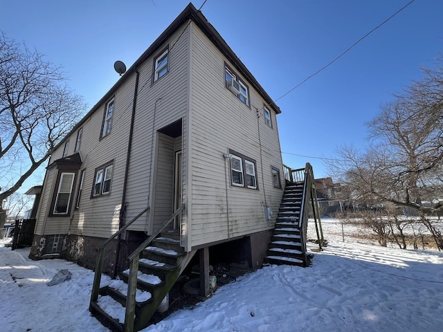 snow covered property featuring stairway