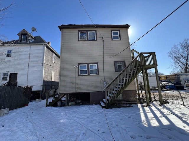 snow covered property featuring fence and stairway