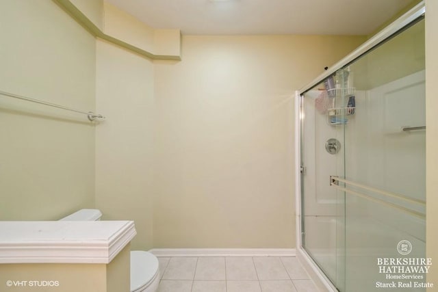 bathroom with baseboards, toilet, a stall shower, and tile patterned flooring