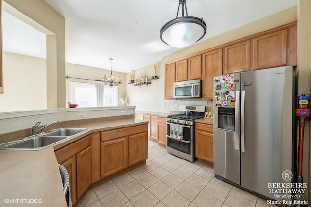 kitchen featuring light tile patterned floors, brown cabinets, appliances with stainless steel finishes, hanging light fixtures, and a sink