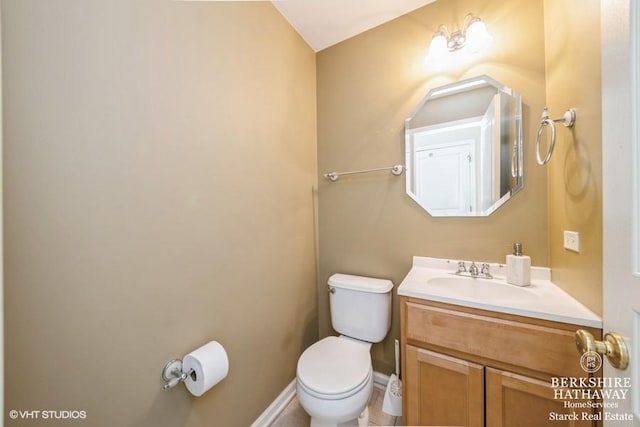 half bathroom with toilet, vanity, and baseboards