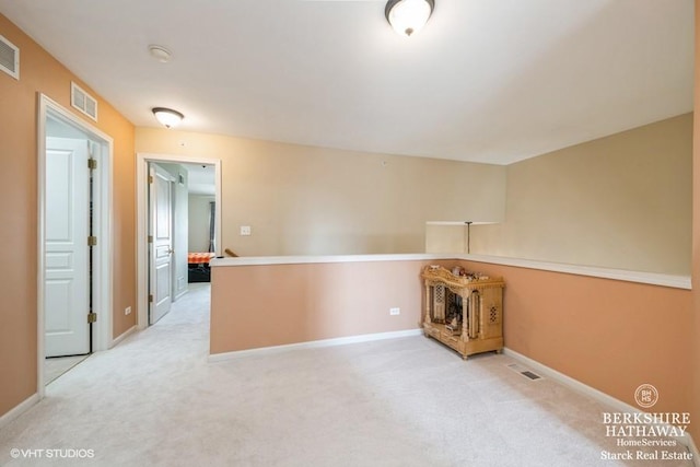 empty room with visible vents, light colored carpet, and baseboards