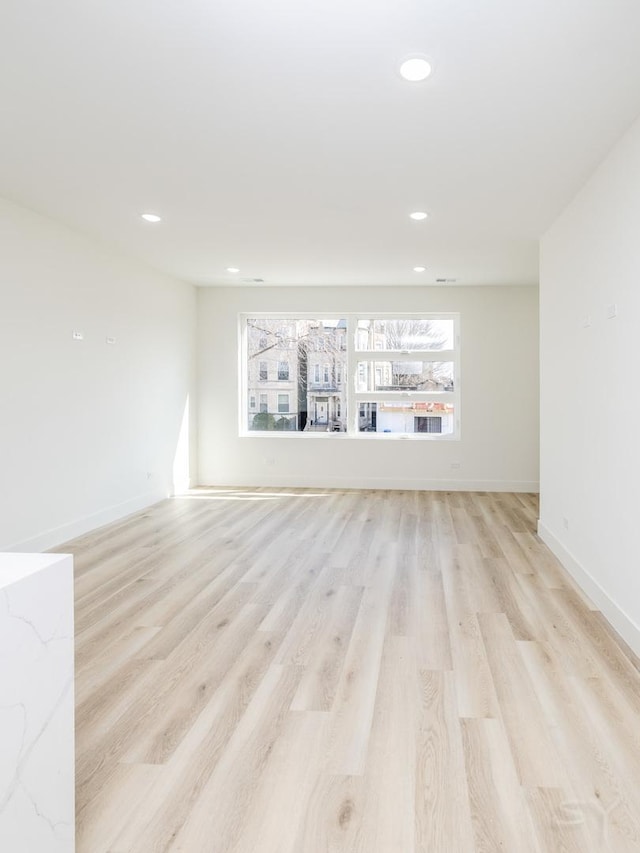 spare room featuring light wood-type flooring, baseboards, and recessed lighting