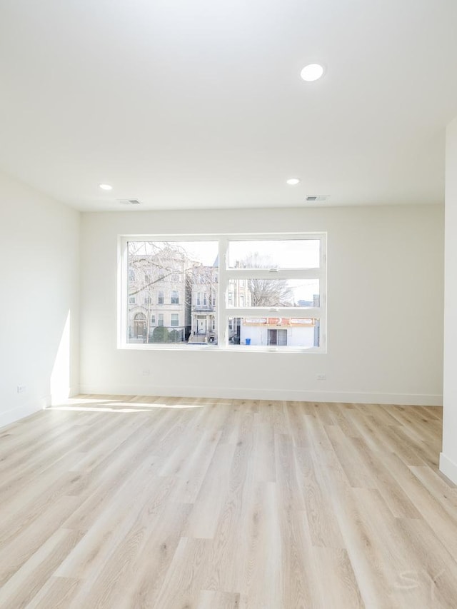 empty room with light wood-style floors, baseboards, visible vents, and recessed lighting