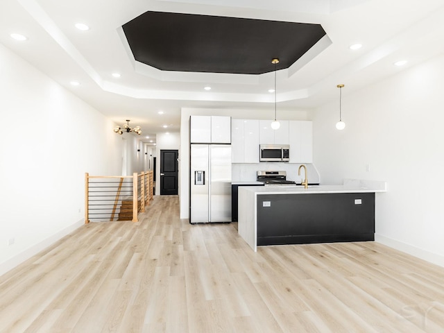 kitchen featuring stainless steel appliances, a raised ceiling, white cabinetry, and modern cabinets