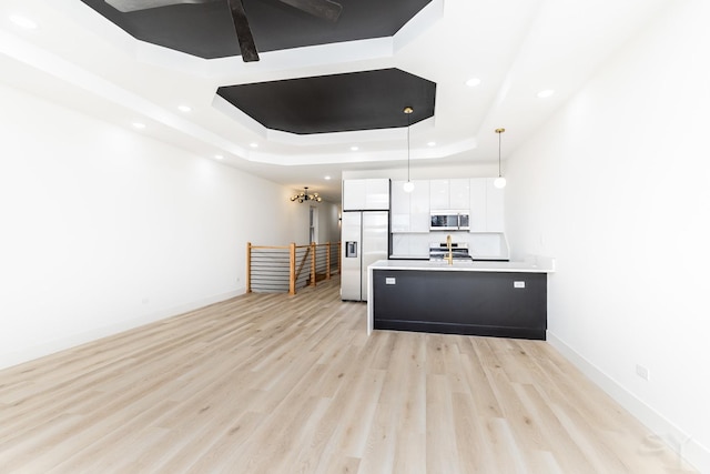 kitchen featuring pendant lighting, a tray ceiling, appliances with stainless steel finishes, and white cabinets