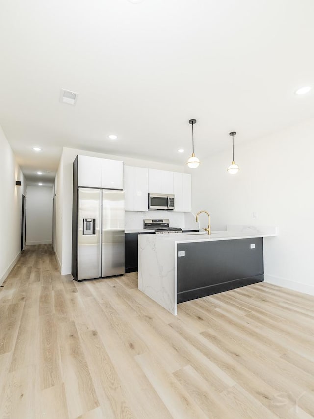 kitchen featuring appliances with stainless steel finishes, decorative light fixtures, light wood-type flooring, white cabinetry, and recessed lighting