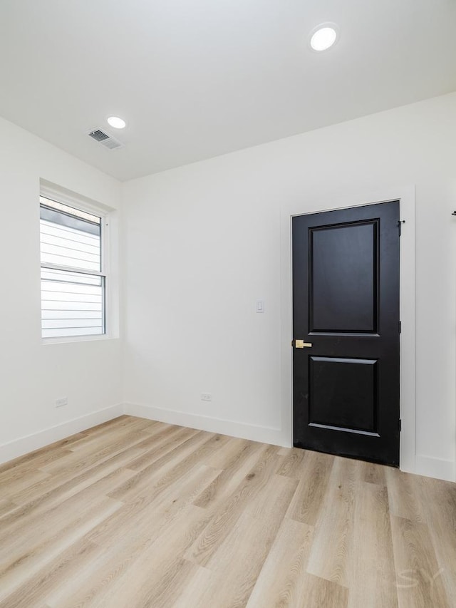 empty room with recessed lighting, wood finished floors, visible vents, and baseboards