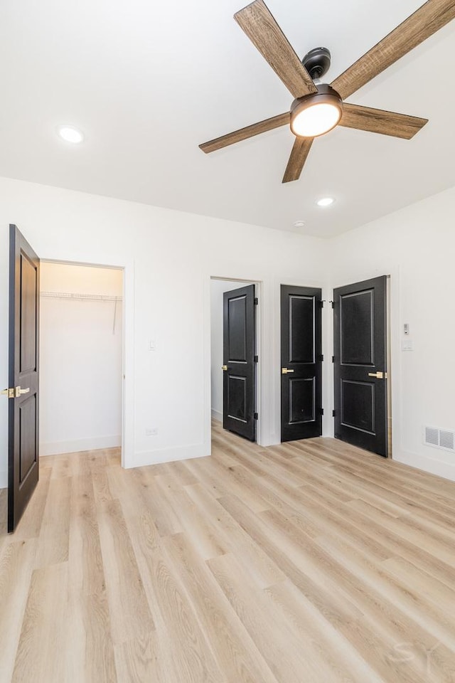 unfurnished bedroom featuring recessed lighting, visible vents, baseboards, light wood-style floors, and a spacious closet