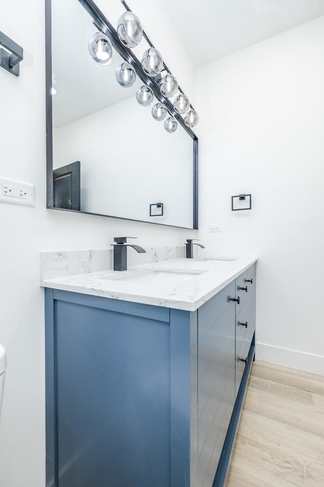 bathroom featuring double vanity, a sink, baseboards, and wood finished floors