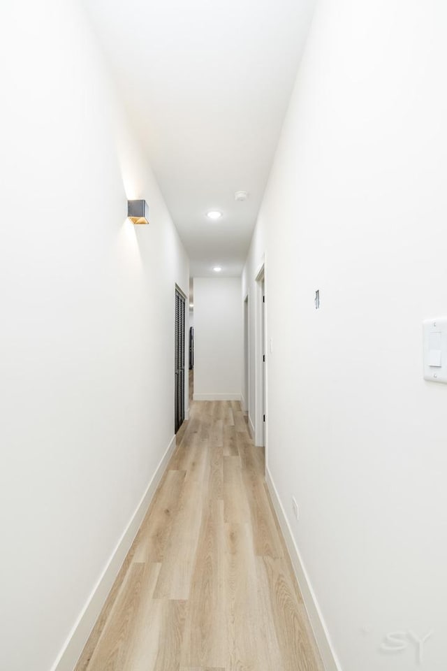 hallway featuring light wood-type flooring and baseboards