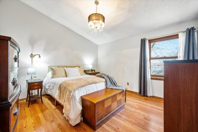 bedroom featuring lofted ceiling, a notable chandelier, baseboards, and light wood finished floors