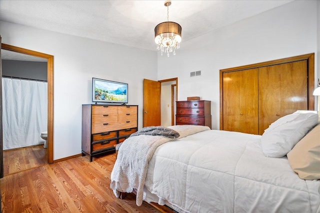 bedroom with visible vents, a closet, light wood finished floors, baseboards, and a chandelier