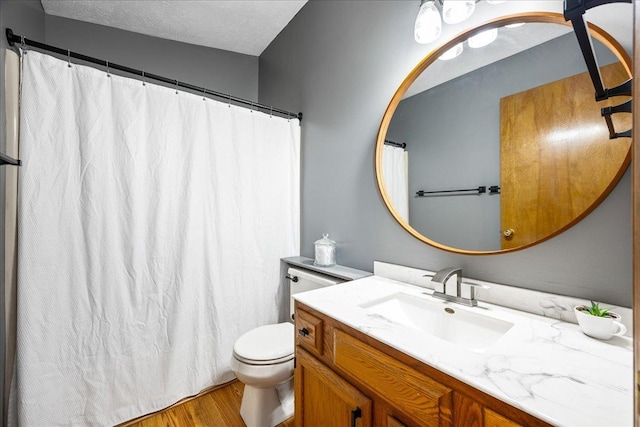 bathroom with a shower with curtain, toilet, a textured ceiling, wood finished floors, and vanity