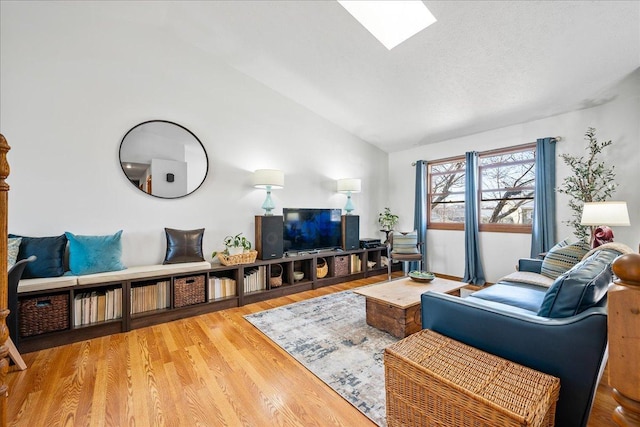 living area with vaulted ceiling with skylight, a textured ceiling, and wood finished floors