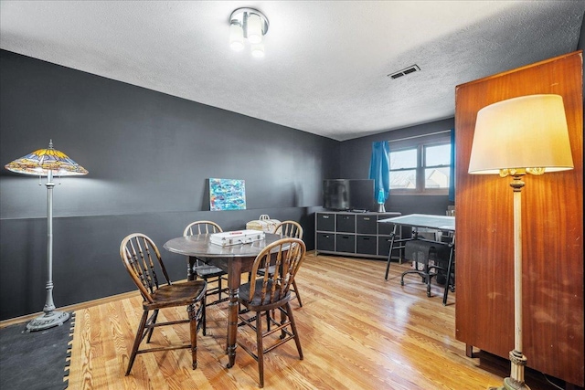 dining space featuring visible vents, a textured ceiling, and wood finished floors