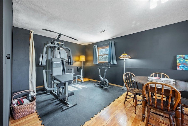 exercise area with baseboards, visible vents, and a textured ceiling