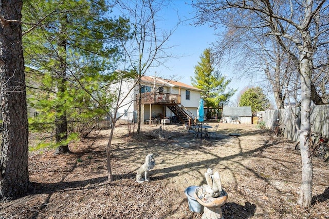 rear view of property with stairs, a storage shed, a fenced backyard, a deck, and an outbuilding