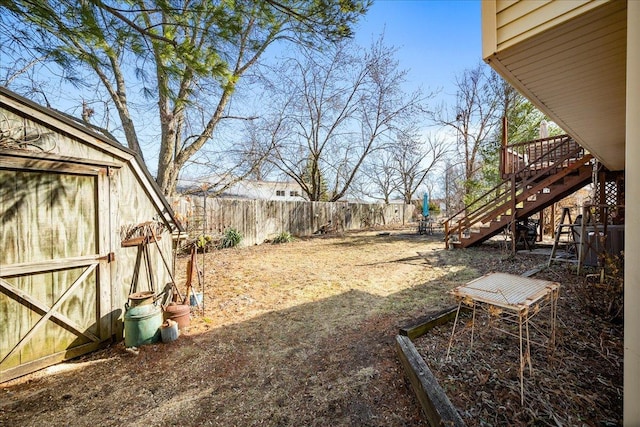 view of yard with a garden, a fenced backyard, and stairs