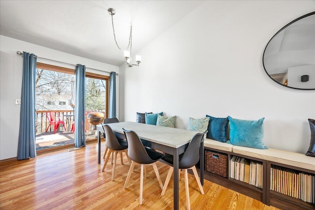 dining area featuring lofted ceiling, an inviting chandelier, and light wood finished floors