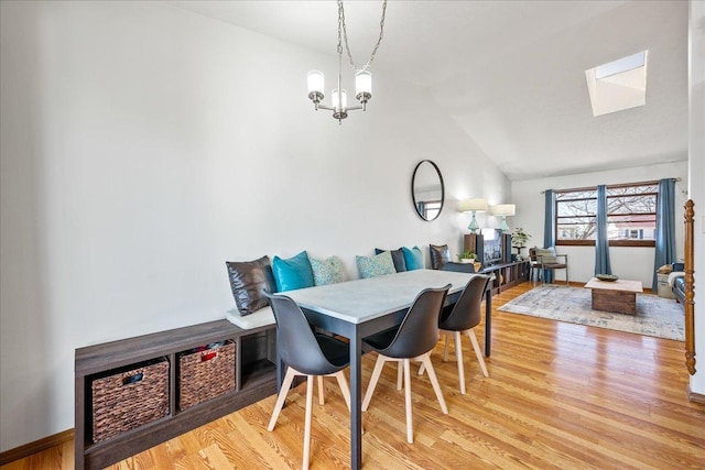 dining room featuring an inviting chandelier, light wood-type flooring, and lofted ceiling