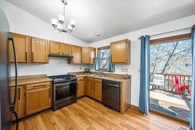 kitchen with lofted ceiling, a sink, light countertops, under cabinet range hood, and appliances with stainless steel finishes