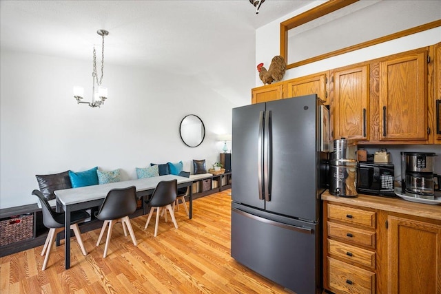 kitchen featuring breakfast area, light wood finished floors, brown cabinetry, and freestanding refrigerator