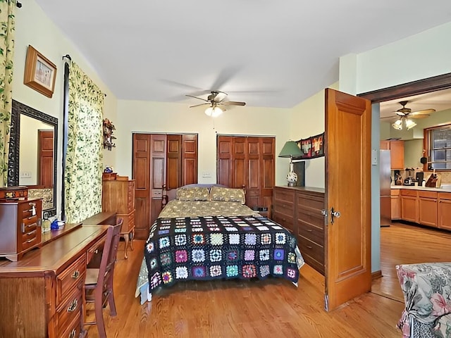 bedroom featuring light wood-type flooring, freestanding refrigerator, and two closets