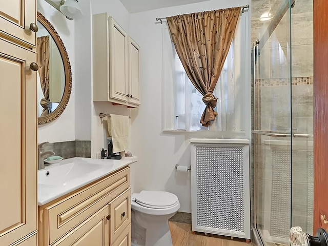 full bathroom featuring toilet, wood finished floors, a shower stall, and vanity